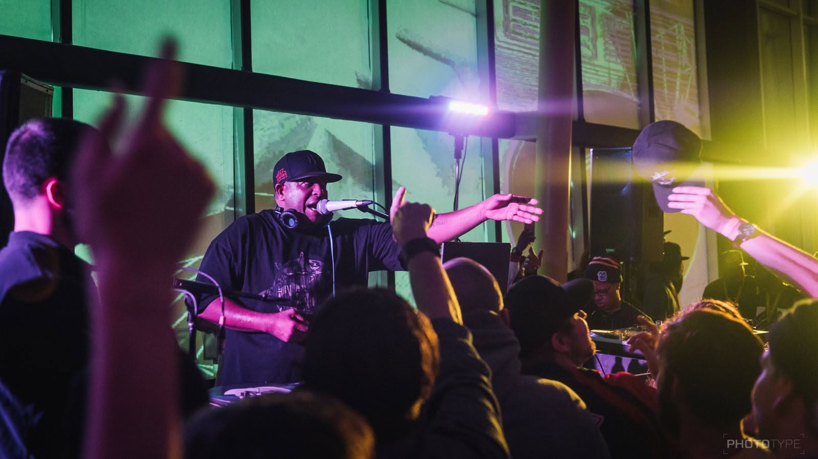 MC reaching toward the crowd during a live performance under colored stage lights