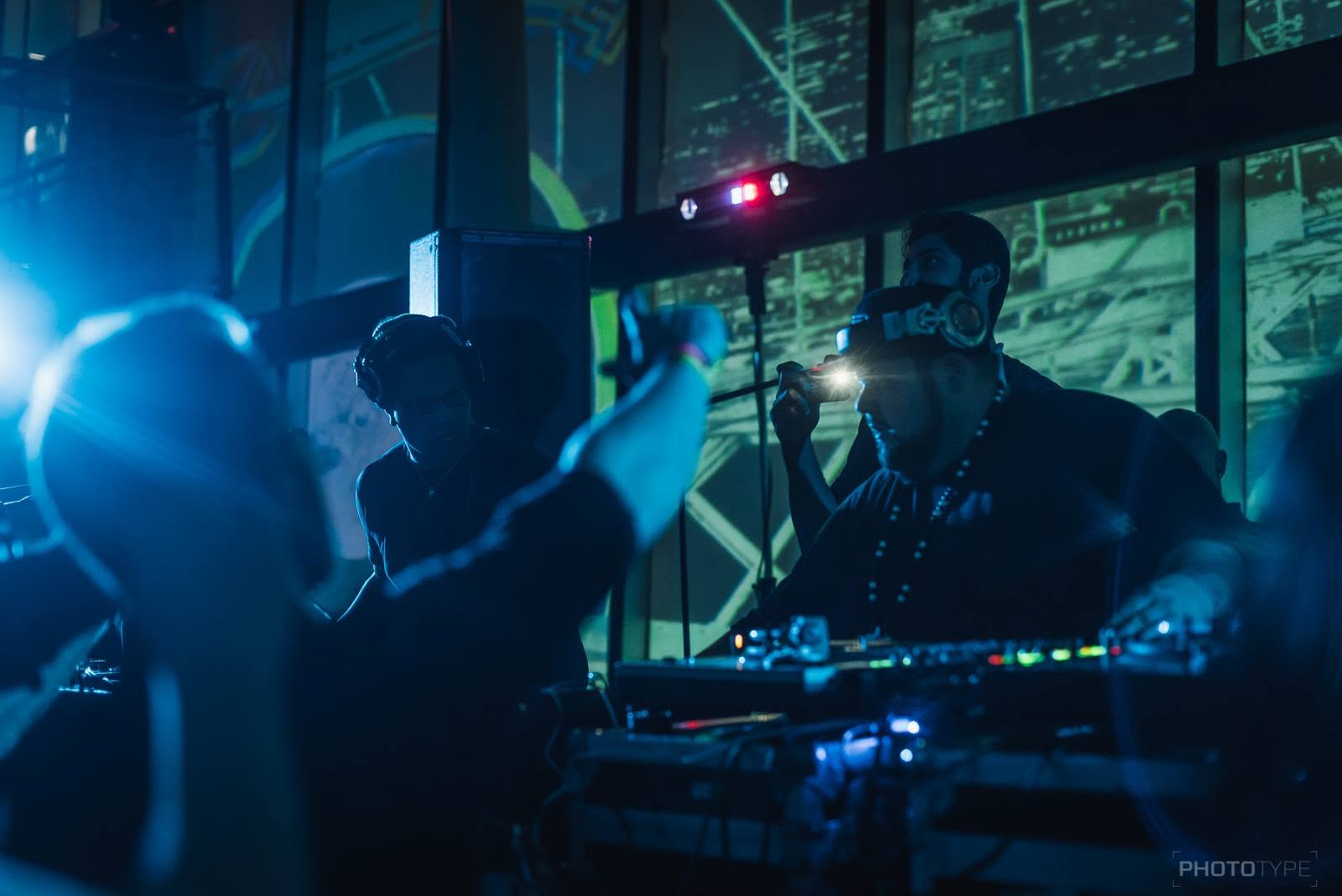 DJs performing at the turntables under blue stage lighting