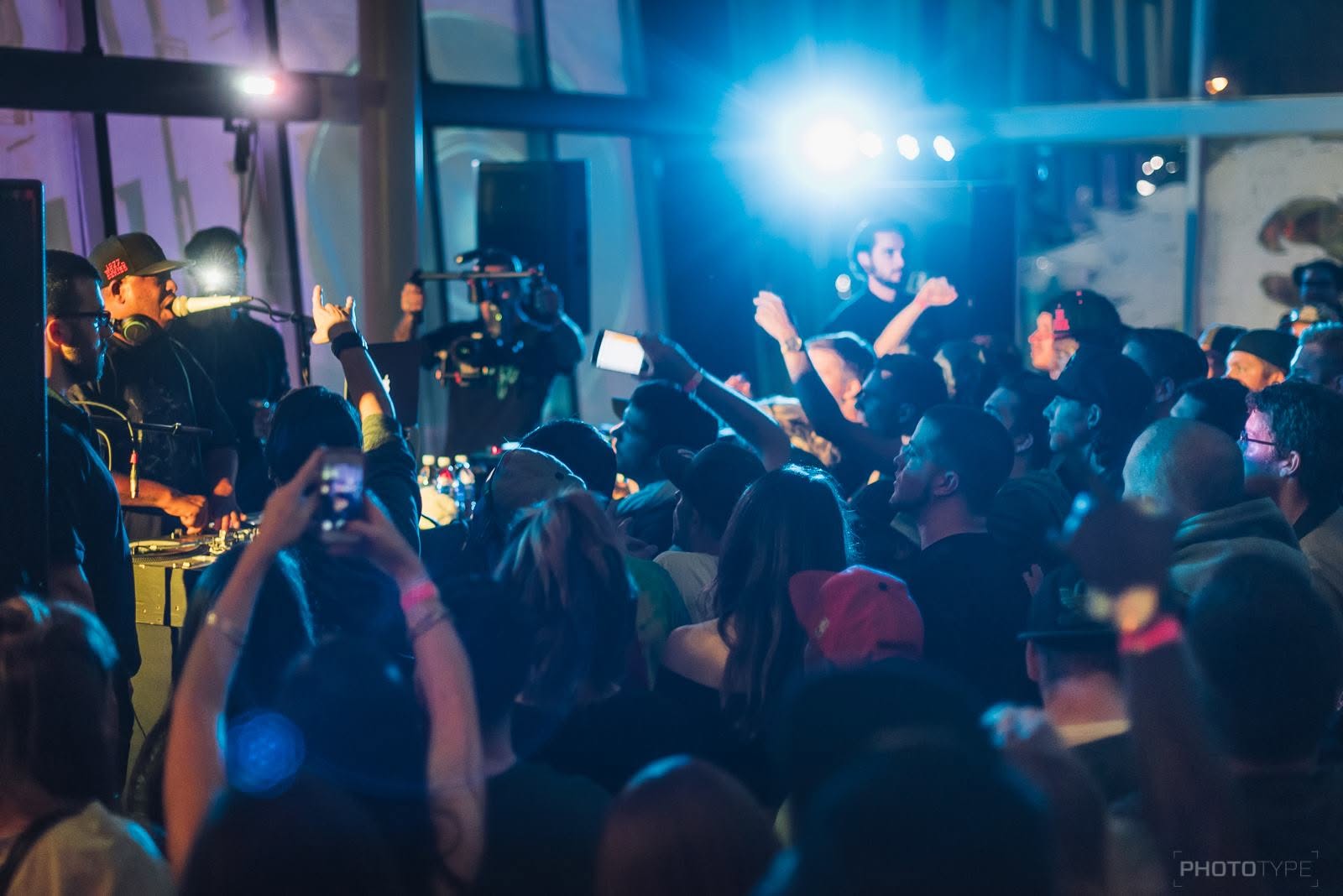 MC performing live on stage with a photographer capturing the crowd