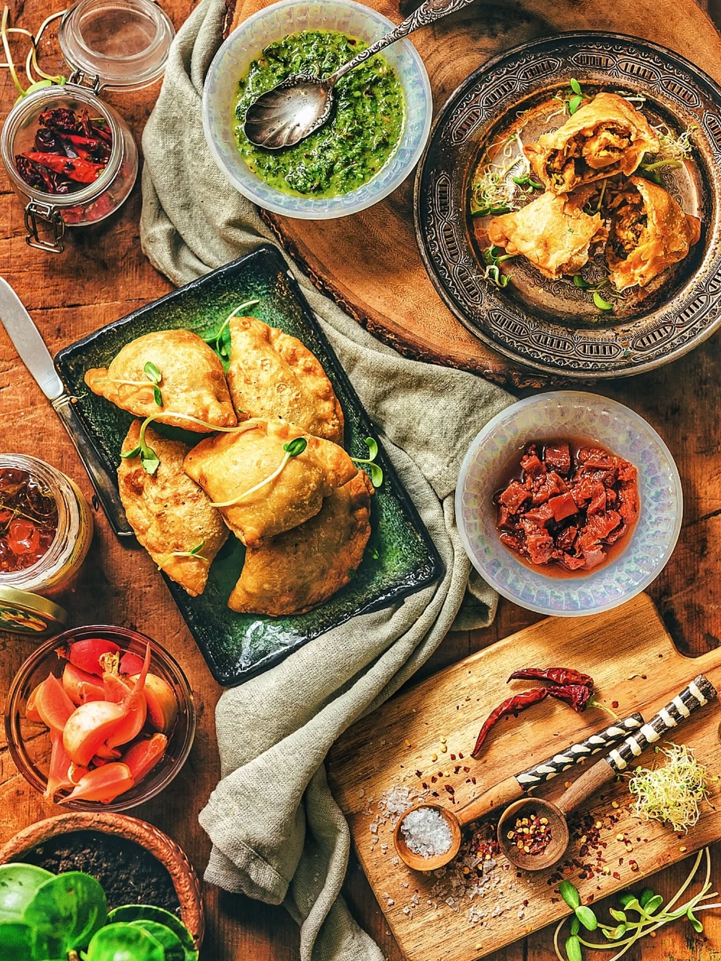 Fried samosas with chutneys, styled overhead on a wooden table